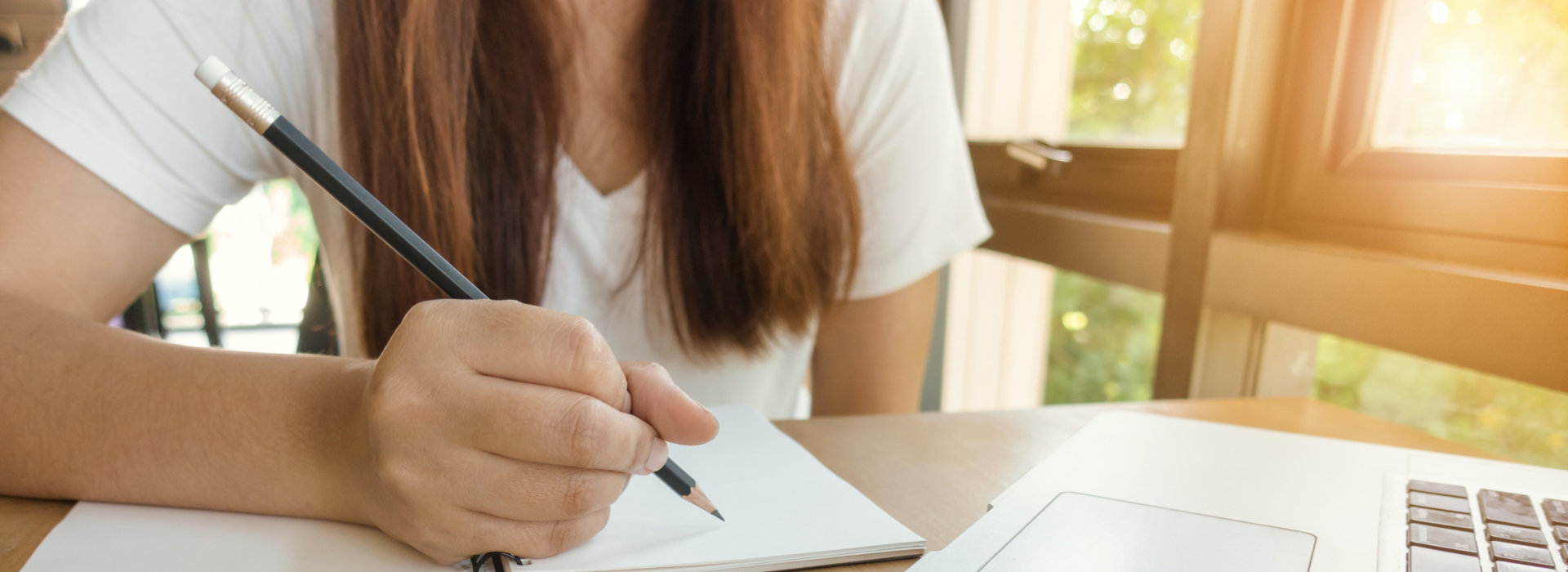 zdjęcie przedstawia kobietę piszącą ołówkiem w notesie